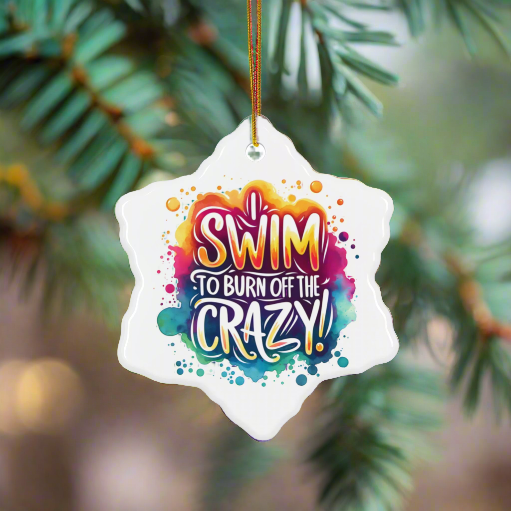 Decorative ornament with colorful text 'SWIM TO BURN OFF THE CRAZY!' hanging on a tree.